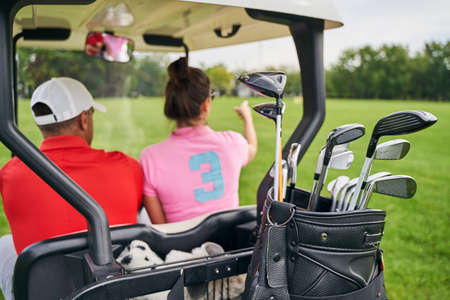 Back view of a dark-haired young Caucasian female golfer pointing at something to a manの写真素材