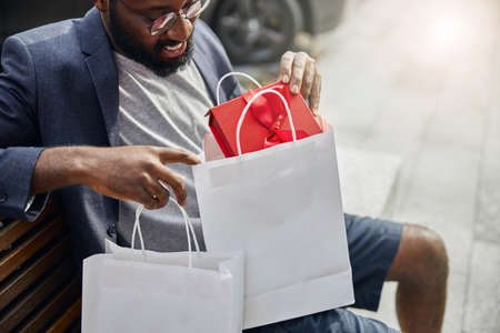 Pleased bearded man demonstrating his friendly smile while preparing present for his partner