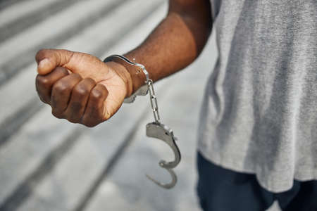 Close up of international male person demonstrating his strength, having handcuffの写真素材