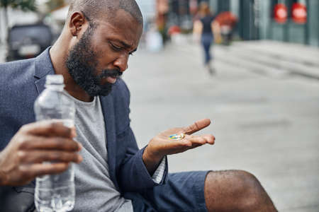 Attentive male person bowing his head while staring at palm with mixed pills