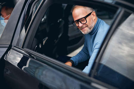 Dreamy handsome man with a pleased smile sitting in the back seat of the taxi