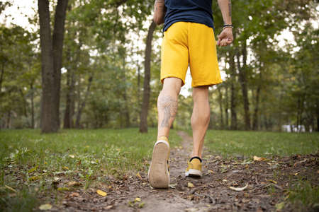 Cropped head close up of muscular male legs while he is doing workout in nature and running