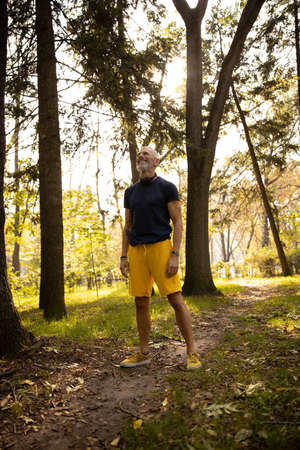 Man is standing in wood while going jogging and exercising in natureの写真素材