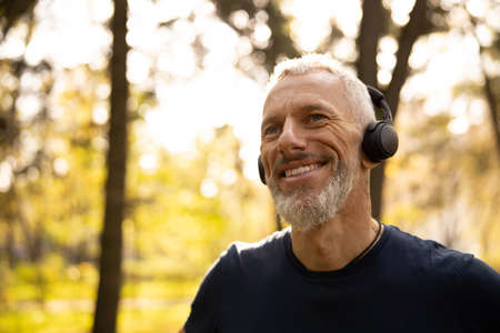 Man is spending free time in forest and relaxing with audio in earphonesの写真素材