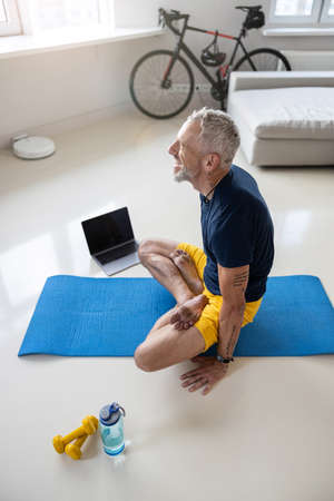 Joyful man pushing himself off the ground with the help of hands while sitting in a lotus postureの写真素材
