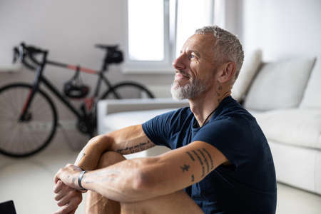 Cropped photo of a pleased athlete clasping his hands with tattoos and staring in front of himselfの写真素材