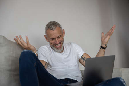 man raising his hands and having no clue what going on the screen of his laptop