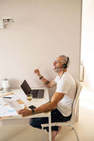 Businessman raising his hand with pencil in delight because of getting a new thought from a chart in...
