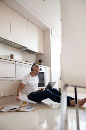 Upset man with a headset putting off a document back to the stack while looking at his notes