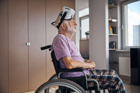 Side view of a calm senior man wearing a virtual reality headset on his head