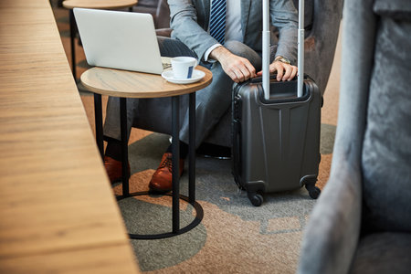 Cropped photo of a person unzipping a rolling suitcase with a handle beside himの写真素材