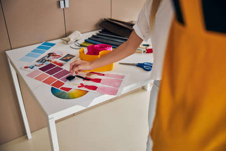 Cropped photo of a blonde Caucasian girl standing at the cutting table in her workshop