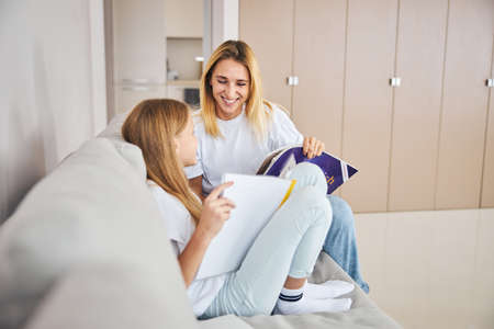 Parent taking a seat next to her daughter on a sofa and feeling joy about her learning progress