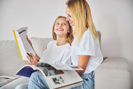 Loving teenager looking at her caring parent and showing a perfectly done exercise in a copybookの写真素材