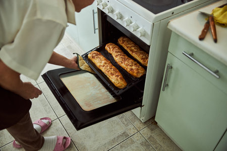 Close up of old female hand getting baking tray with delicious baked pies out of ovenの写真素材