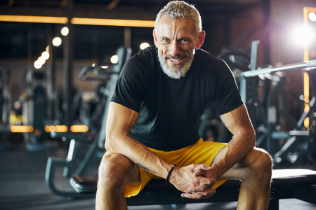 Front view of a smiling pleased bearded gray-haired male athlete with interlocked fingers looking aheadの写真素材