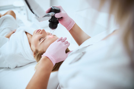 Cropped photo of a female dermatologist directing a laser beam at the young patient foreheadの写真素材