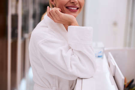Cropped photo of a joyful young Caucasian lady resting one elbow on the reception deskの写真素材