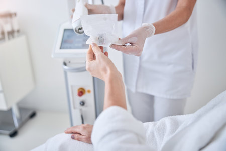 Close up image of doctor hands in protective gloves giving medication treatment preparation to her patient in beauty clinicの写真素材