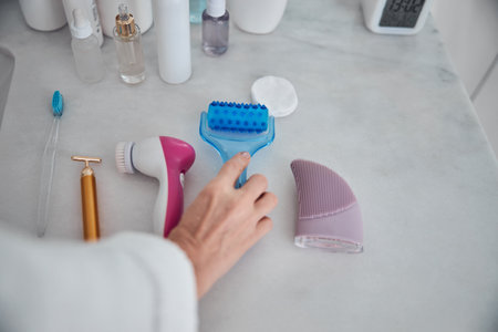 Close up portrait of beautiful female hand holding blue roller massager in bathroomの写真素材