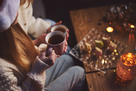 Top view cropped head of loving mother and daughter drinking tea with macaroons at Christmas togetherの写真素材