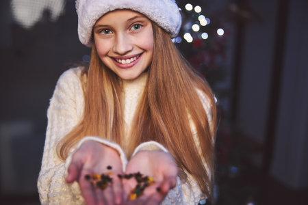 Portrait of joyful beautiful teenage girl is shooting crackers while celebrating Christmas in cozy houseの写真素材