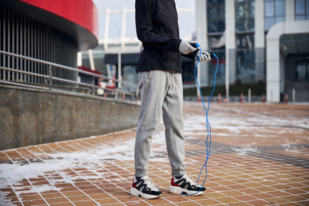Sportsperson standing with her feet pressing a blue rope to the bricks of a squareの写真素材