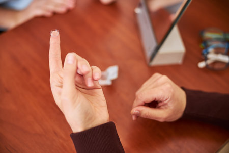 Clear eye lens lying on a fingertip of a medical person, raising her hand above a deskの写真素材