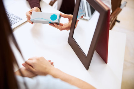 Cropped photo of contact lenses envelope being held next to a mirror by a medic