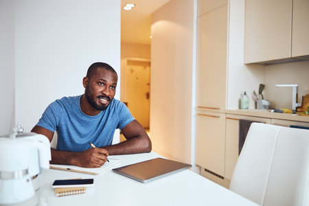 Man looking up in a distance searching for new ideas for his writing while sitting over a record bookの写真素材
