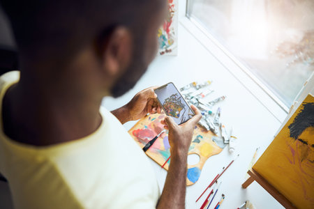 Artist keeping a phone with both hands over the painting tools and taking their pictureの写真素材