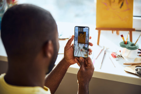 Person taking a photo of a drawing and painting appliances on a cellphone and watching the resultの写真素材