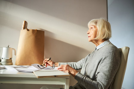 Side view of a thoughtful woman with a pen in one hand looking into the distanceの写真素材