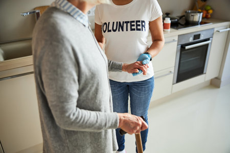 Cropped photo of a blonde elderly lady standing in the kitchen supported by the armの写真素材