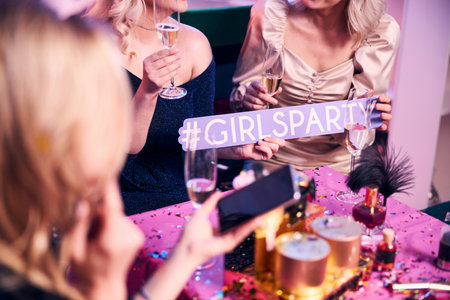 Cropped photo of a woman with a smartphone sitting at the festive table with her colleaguesの写真素材
