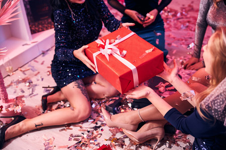Cropped photo of a seated bride-to-be with a short bridal veil receiving a present box on the floorの写真素材