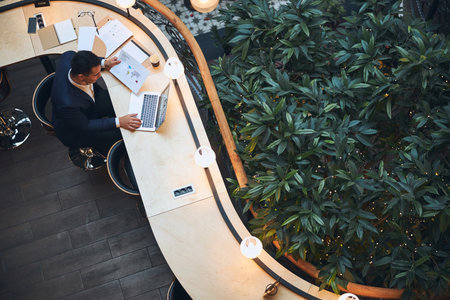 Top view of a stylish male with short dark hair sitting at the table in the coworking spaceの写真素材