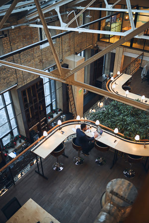 Back view of a man with a pair of eyeglasses in his hand listening to his coworker via Skypeの写真素材