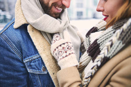 Cropped head of smiling man and woman looking with love at each other while spending snowy day outdoorsの写真素材