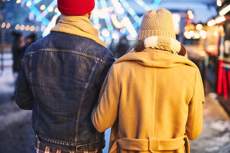 Romantic man and woman are spending time together in open air in lighted city centre at Christmasの写真素材