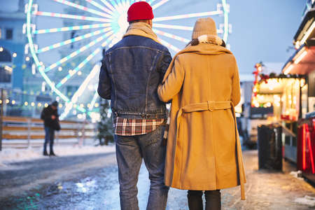 Romantic man and woman are spending cold day outdoors and going to ferris wheel during holidaysの写真素材