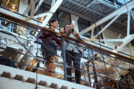 Cute international woman keeping smile on her face while listening to her friendの写真素材