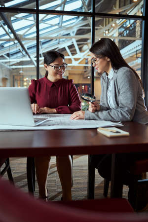 Attentive brunette woman sitting in semi position and looking attentively at drawingの写真素材