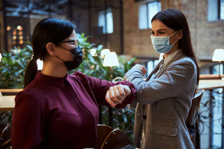 Attentive Asian woman raising her arm while welcoming her business partner