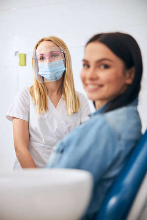 Cheerful brunette visiting her dentist, keeping smile on face while looking at cameraの写真素材