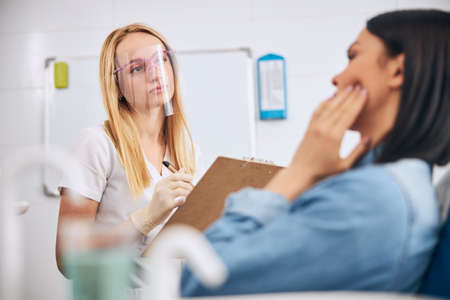 Attentive stomatologist holding folder in her hand during communication with patientの写真素材