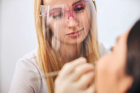 Young blonde woman wearing uniform while doing teeth treatment procedure for her patientの写真素材