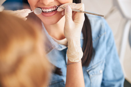 Delighted patient expressing positivity while doing professional teeth cleaning, looking at her...