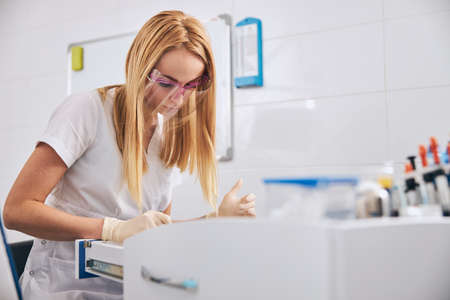 Young concentrated dentist bowing her head while preparing for teeth treatmentの写真素材