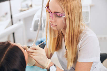 Professional dentist wearing mask while working with patient, doing teeth checkupの写真素材